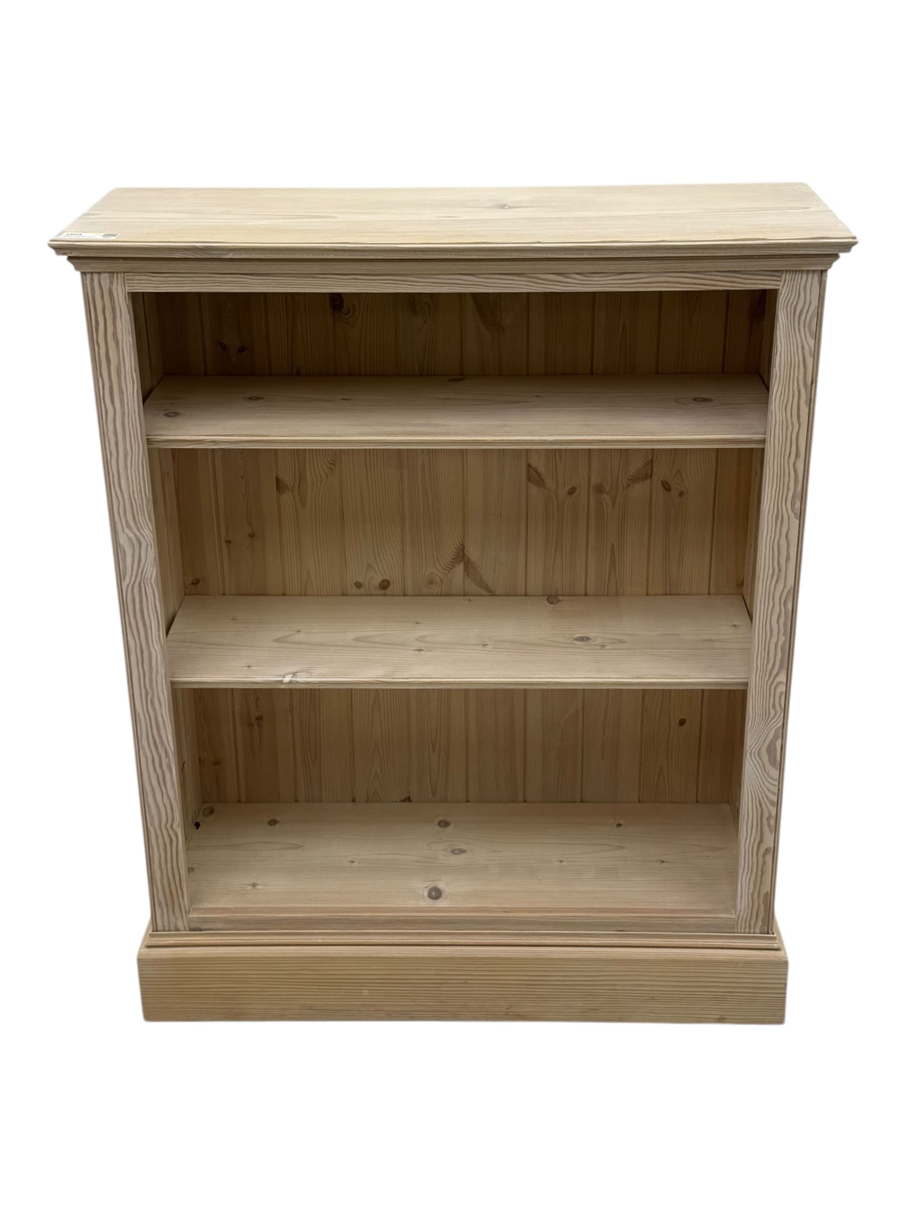 Contemporary light pine open bookcase, rectangular top with stepped moulded edge above a boarded back, fitted with two adjustable shelves, on a plinth base