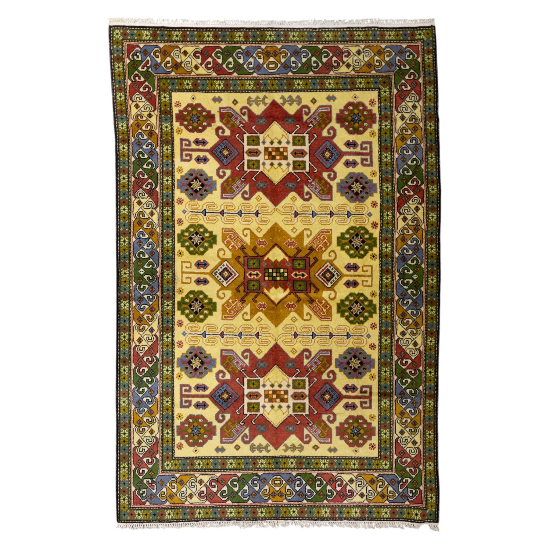 Caucasian Kazak design wool rug, cream field with three large geometric medallions and stylised hooked motifs, enclosed by polychrome reciprocal border and green floral guard stripes