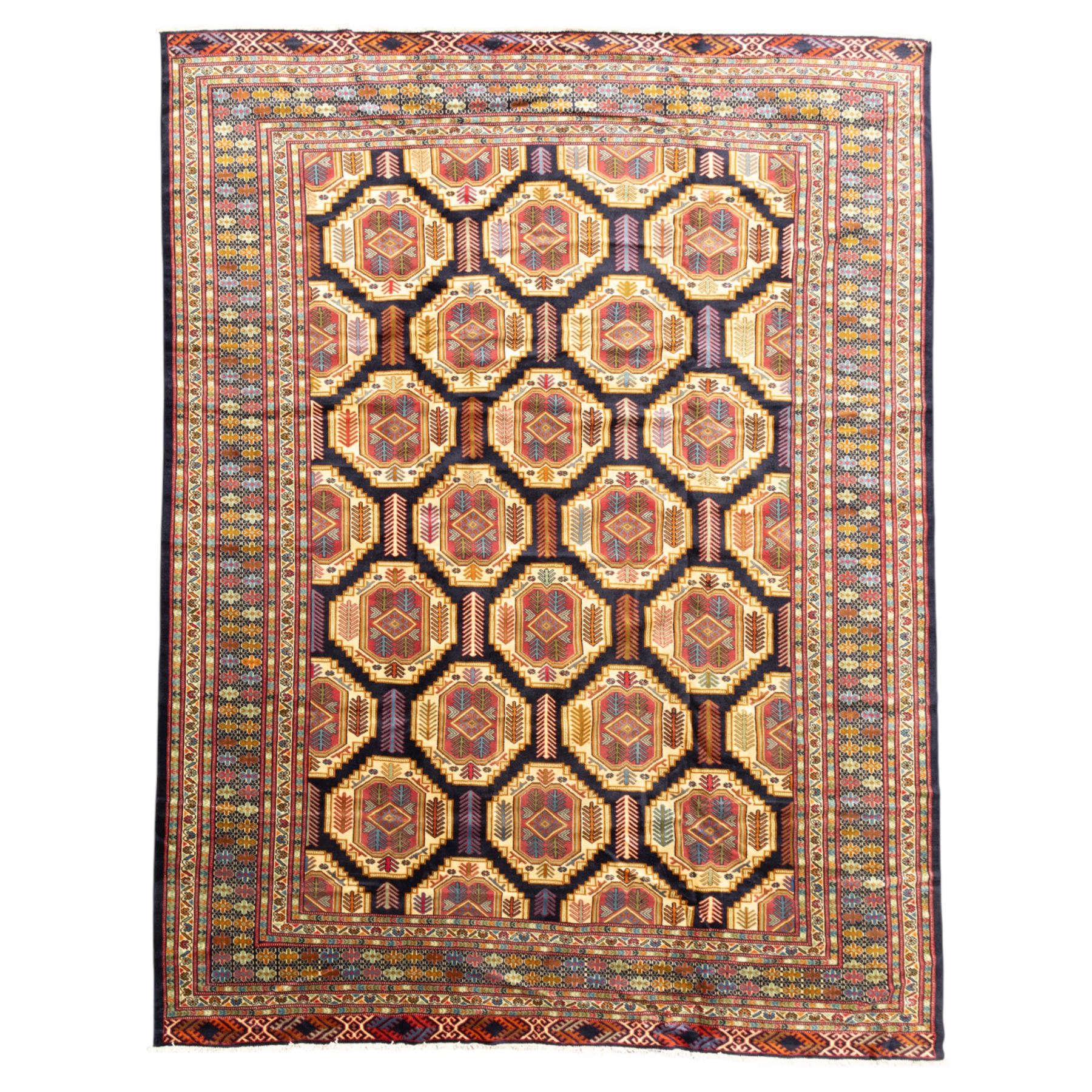 Central Asian Turkmen, main field with octagonal guls enclosing hooked diamond motifs in shades of madder gold, ivory, and indigo set against a dark ground within multiple polychrome borders of geometric devices and stepped motifs 