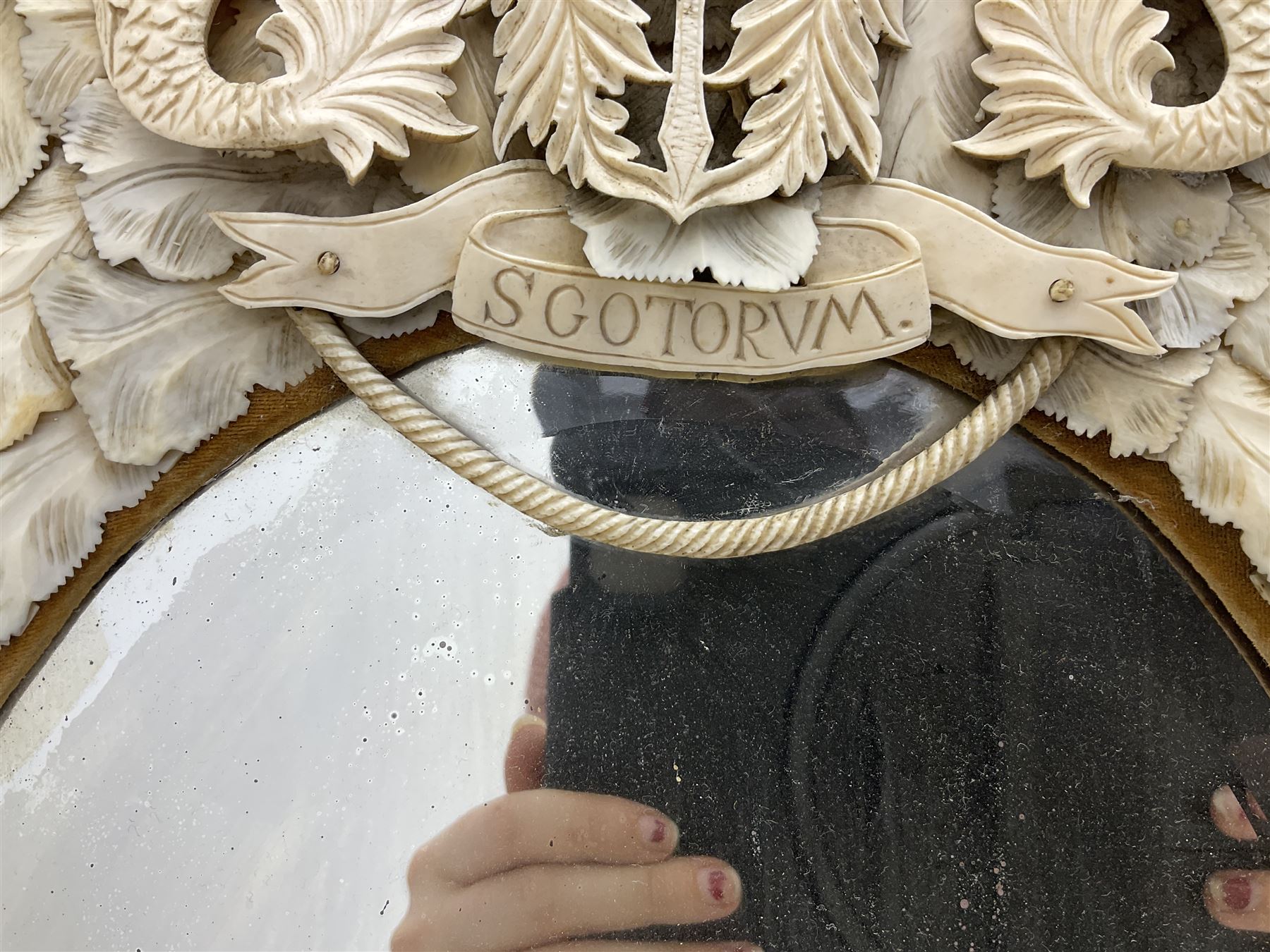 Pair 19th century French Dieppe bone and ivory wall mirrors, the oval bevelled mirror plates within rectangular frames with shaped tops, profusely decorated with ivory leaves, further detailed with carved bone armorial type crest inscribed 'SGOTORVM', putti, fish and mask heads, H81cm W48cm