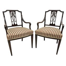 Edwardian mahogany framed three-piece salon suite - two-seat sofa, stepped cresting rail over acanthus and scroll carved pierced splat, upholstered in striped fabric (W124cm, H87cm, D62cm); and a pair of matching armchairs (W60cm) 