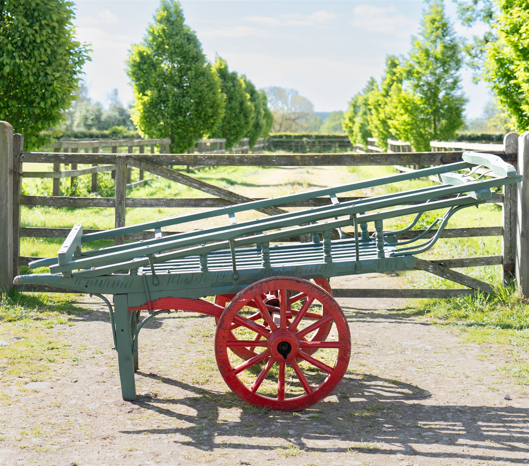 Costermonger’s Cart

A painted costermonger’s cart with green slatted timber body, red painted wooden spoked wheels and red leaf spring suspension. The cart is fitted with raised side rails, turned supports and short projecting handles. Painted lettering is visible along the side rails, together with the number “661” to the frame and wheel rim.
Finished in traditional colours, the cart offers excellent decorative appeal and would be suitable for display, garden or country house settings.

Dimensions:
Overall length: 240 cm
Body length: 215 cm
Width: 94 cm
Height: 86 cm
Wheel diameter: 64 cm

Features:
Timber construction
Open slatted carrying platform
Shaped side rails
Leaf spring suspension
Wooden spoked wheels
Iron tyres
Iron fittings throughout
Carved ownership and maker inscriptions
Traditional painted finish

