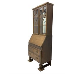 Early 20th century oak bureau bookcase, two astragal glazed doors enclosing two adjustable shelves with mirror back, fall-front concealing fitted interior over two drawers, raised on lobed baluster supports with stretcher base