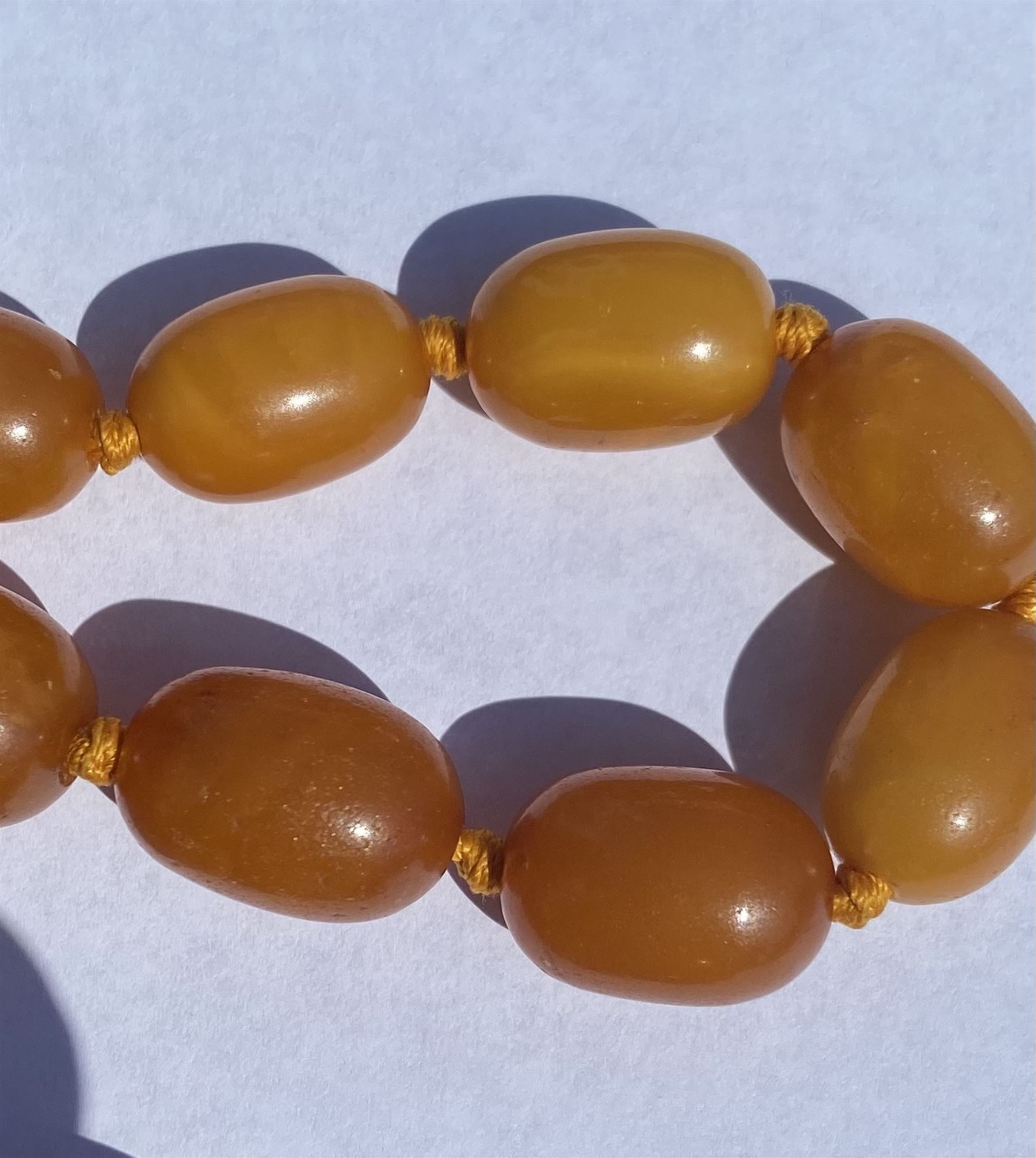 Single strand graduating oval butterscotch amber bead necklace, with three additional loose amber beads