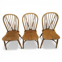 Traditional elm and beech Windsor dining chairs, each with hoop back and turned spindles over a shaped solid seat fitted with loose floral upholstered cushions, raised on turned tapering supports united by crinoline stretchers