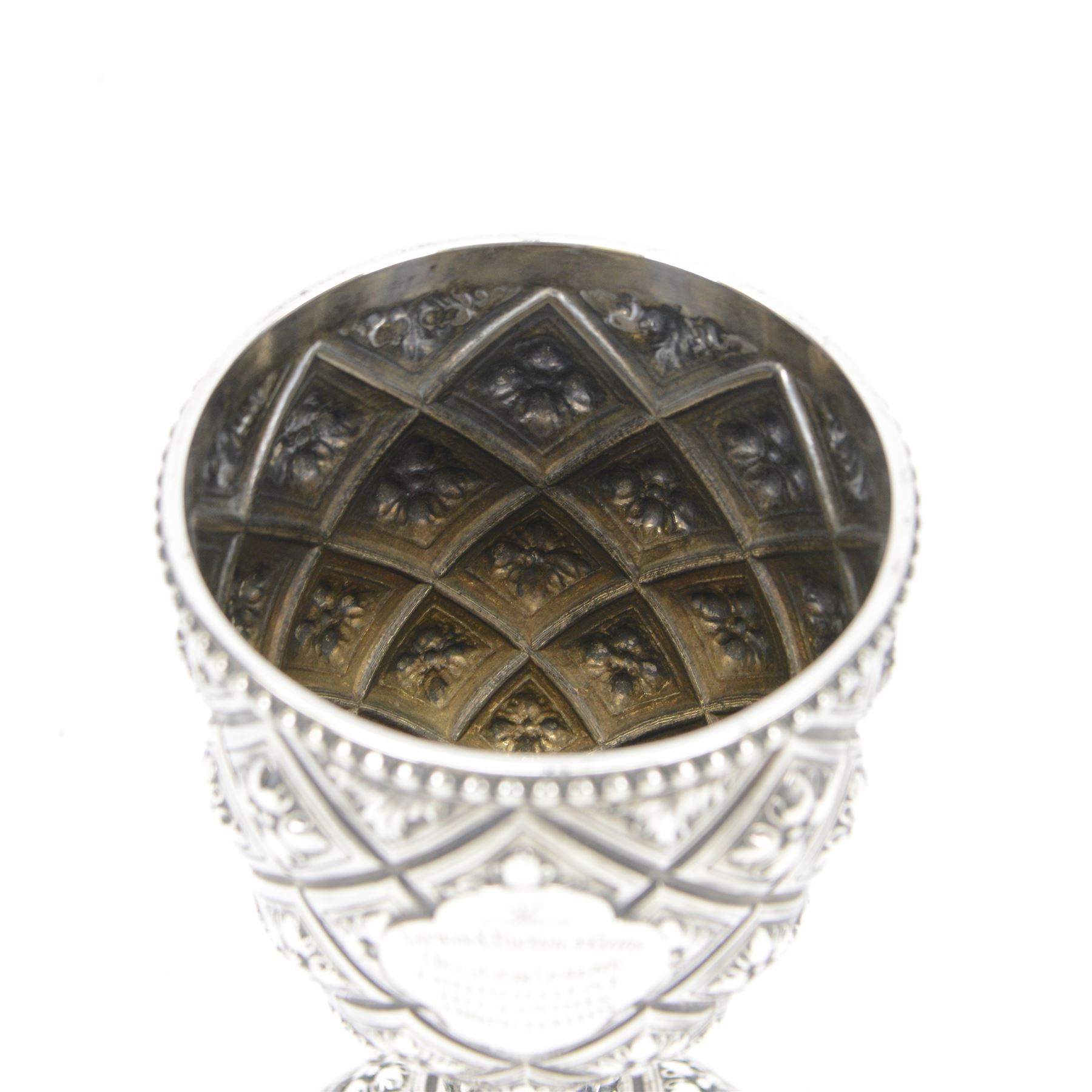Victorian silver trophy cup or goblet, the cup with personally engraved quatrefoil panel and beaded rim, upon a knopped flower head detailed stem and spreading circular foot, embossed throughout with a flower head diamond trellis pattern, hallmarked Robert Hennell III, London 1860, H18cm