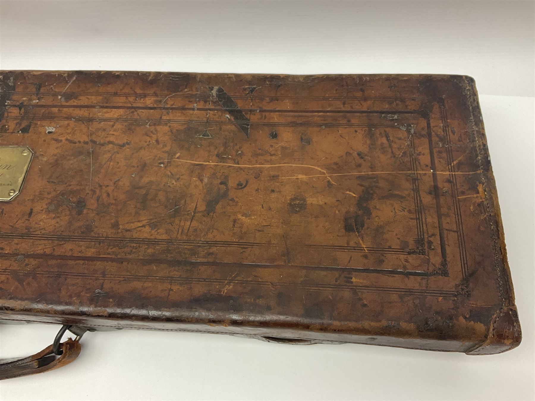 Leather shotgun case, the red baize lined interior with the trade labels of Westley Richards & Co., London, a brass plaque inscribed 'T Nevin, Mirfield, Yorkshire' to cover, with key, case to fit barrel 76cm (30 inches)  
