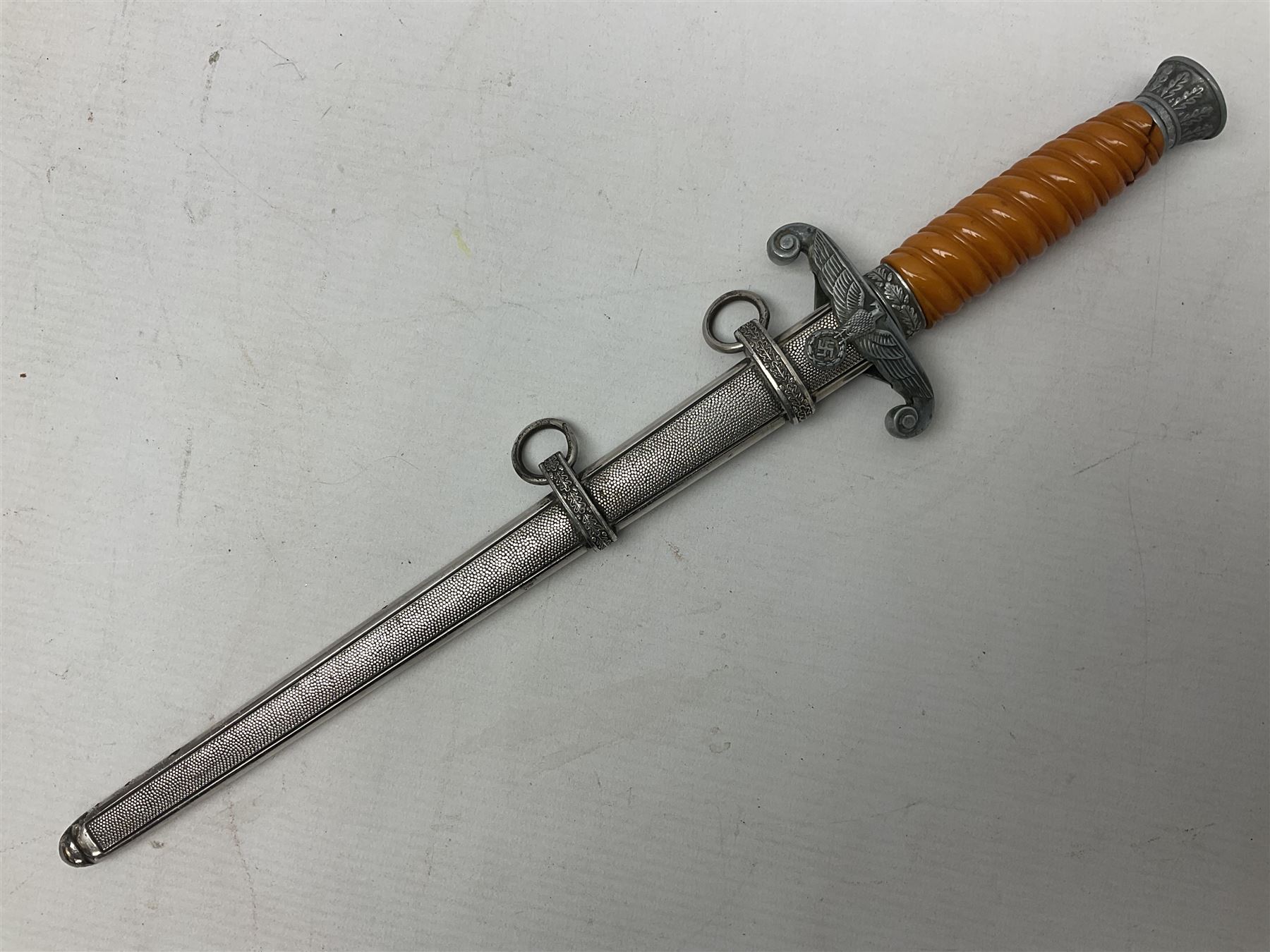 Late WW2 German Army Officers dress dagger, with unmarked 25cm double edged steel blade, orange celluloid grip, pommel and ferrule with oakleaves relief and cross guard with eagle; in original beaded scabbard with two hanging rings L39.5cm overall