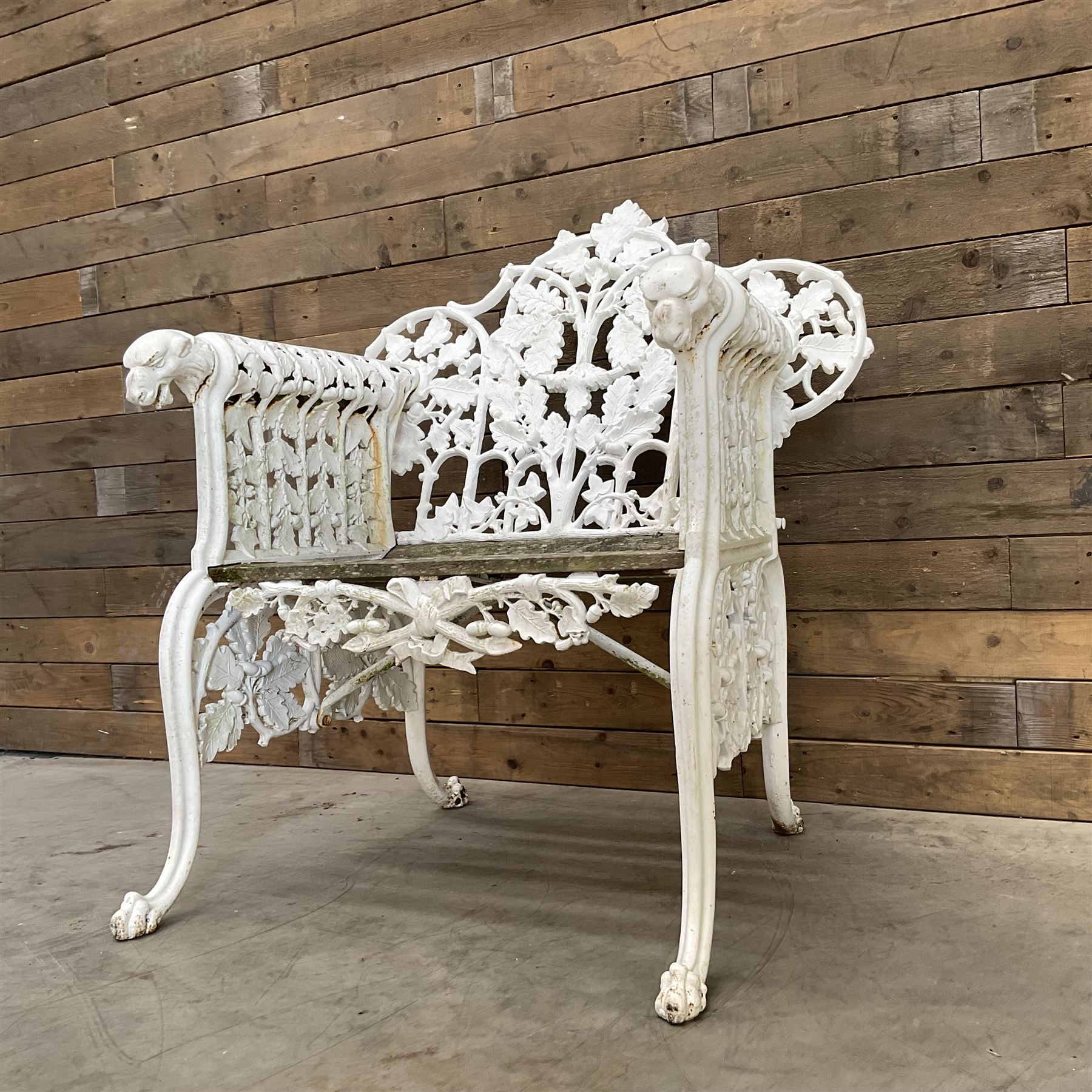 20th century Coalbrookdale design cast iron oak leaf and acorn armchair, white painted cast iron frame with slatted wooden seat, the pierced and shaped back decorated with scrolling oak branches and leafage, flanked by dog mask arm terminals over cabriole supports with paw feet