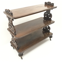  Victorian mahogany three tier dumb waiter, carved and pierced supports on brass castors, W130cm, H122cm, D56cm  