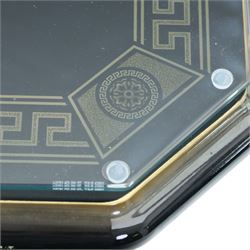 Italian Neoclassical inspired ebonised gloss coffee table, glazed cantered top with Greek key banding, on a shaped pedestal base with gilt highlights and stepped plinth 