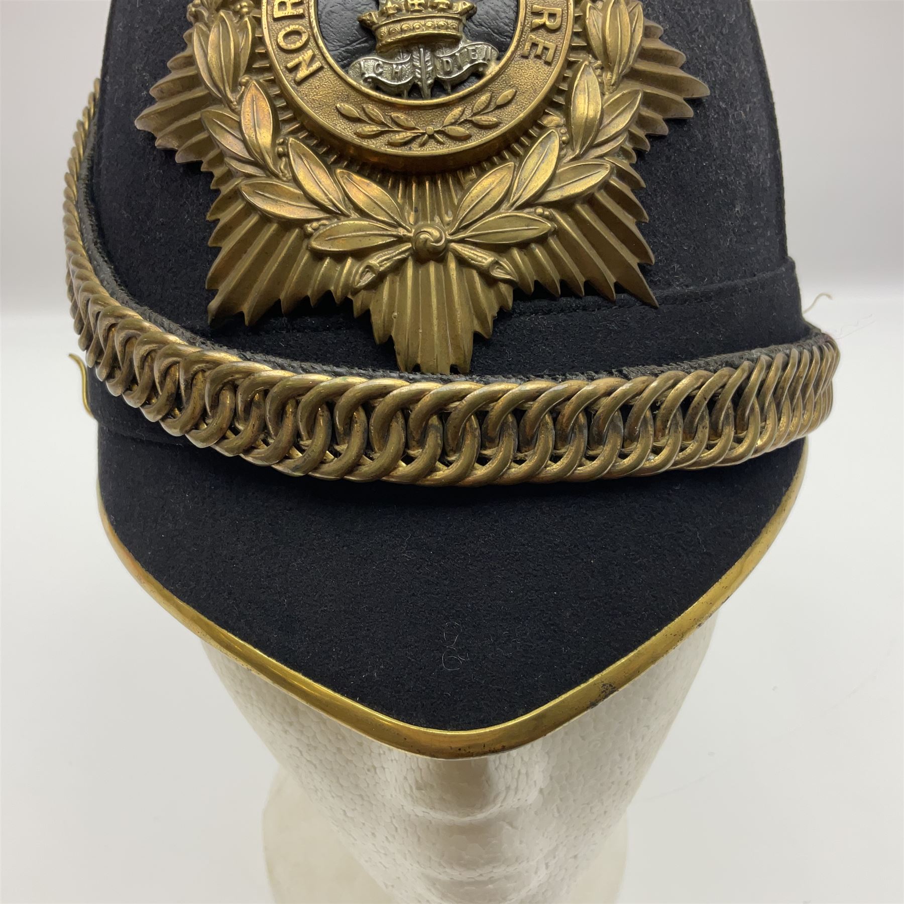 Late Victorian North Staffordshire Regiment Officer's Home Service Blue Cloth Helmet, having incorrect other ranks gilt metal Queen's crown helmet plate to the front with later leather backing, removable spike to the top on a shaped cruciform base with rosette fittings, rosette side bosses, brass trim to the front peak, and leather and velvet backed chin scales, with leather sweat band, the interior with makers stamp for Hawkes & Co 14 Piccadilly London