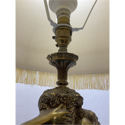 Gilt metal table lamp, modelled as a putti holding aloft a cornucopia of flowers, upon a marble effect and ornate gilt metal base, with fabric tassel lamp shade, total H92cm