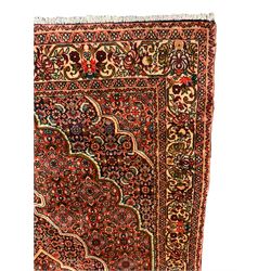 Persian Bidjar crimson ground rug, thick woollen pile, the field decorated with repeating Herati motifs within cusped outlines, the guarded border decorated with repeating flower head motifs