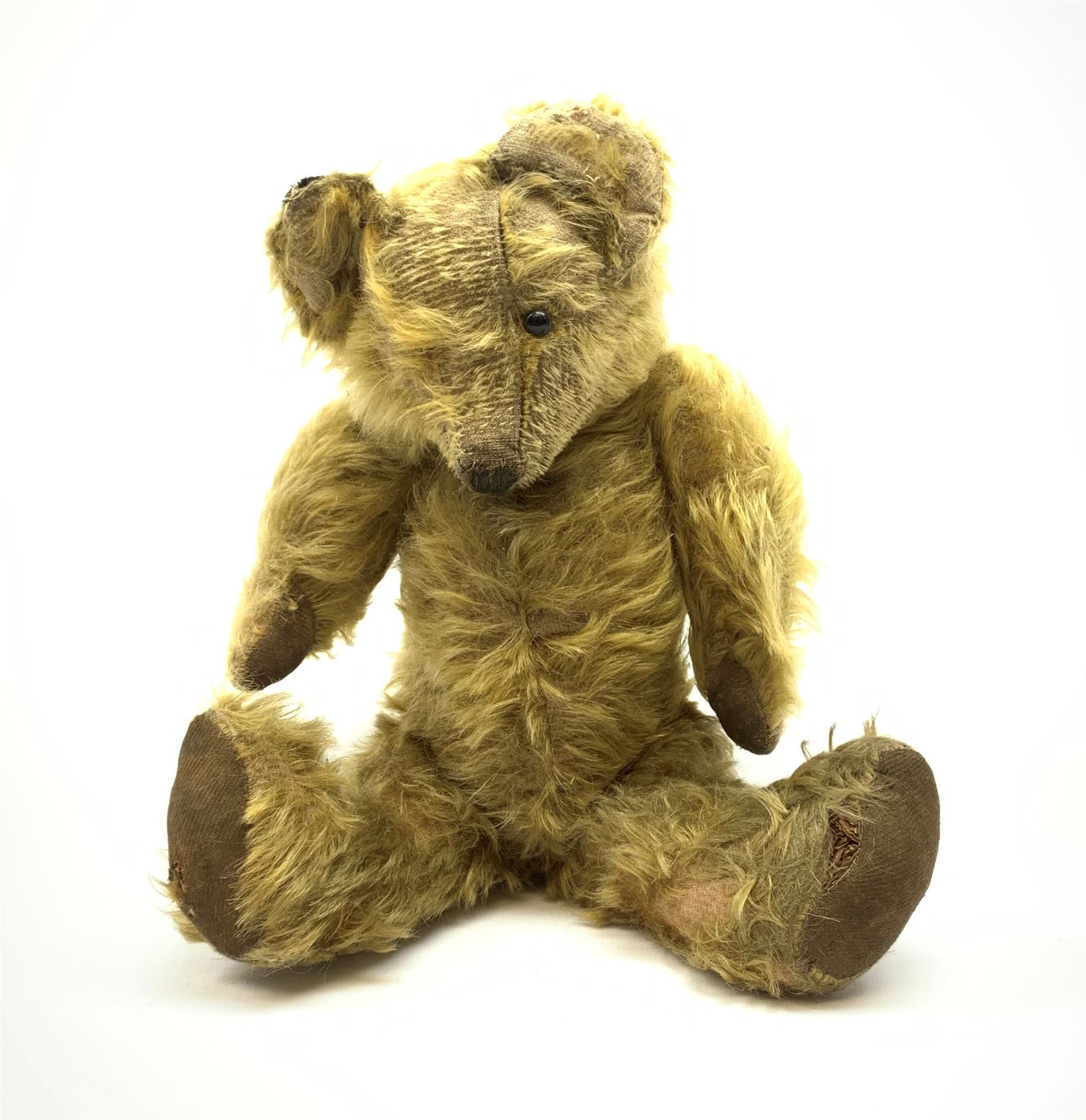 Early 20th century English teddy bear, WW1 period, with wood wool filled mohair body, fixed head with one boot button eye and vertically stitched nose and mouth and jointed limbs with cloth paw pads H16