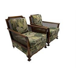 Early 20th century bergère lounge suite, mahogany framed with cane work back and sides, acanthus scroll carved uprights - three seat sofa (W167cm, H82cm, D83cm), and pair matching armchairs (W78cm), loose cushions upholstered in acanthus leaf scroll fabric with scatter cushions