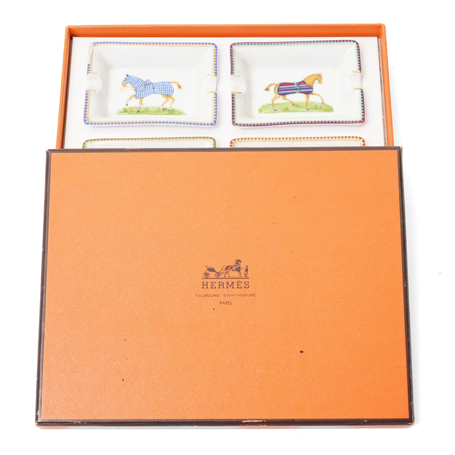 Hermès - set of four miniature porcelain ashtrays, each decorated with a horse in differing blanket, with gilt and coloured borders, in contrasting colour with various horse-coats, in original fitted box