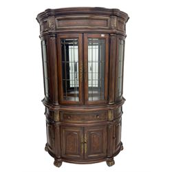  Kevin Charles American walnut demi lune display cabinet with illuminated interior, projecting cornice, two bevel edge glazed doors enclosing two adjustable shelves above single drawer and four cupboard doors with wine rack, carved scrolling supports