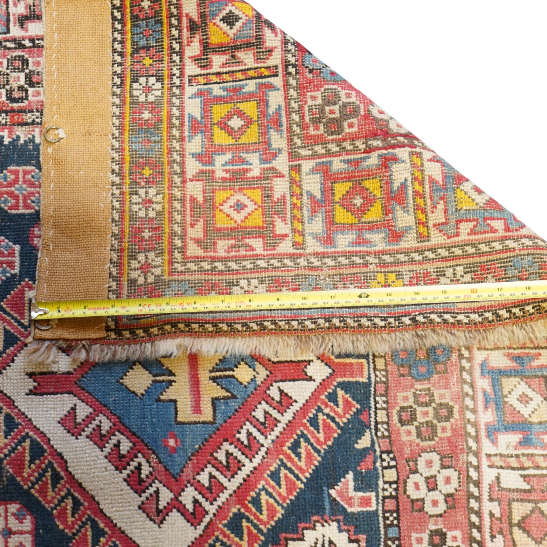 Vintage Caucasian Shirvan hand-knotted rug, indigo field with an arrangement of geometric diamond medallions and stylized tribal motifs within multiple patterned borders, with fringe ends 