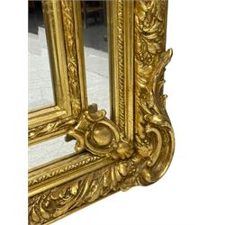 Large Italian Baroque design gilt wall mirror, the shell pediment over circular panel depicting classical female flute player with dancing putto within a tree landscape, the stepped arched upper frame surmounted by musical instrument playing putto and trailing flower heads, central bevelled mirror plate surrounded by plain segmented mirror plates, acanthus leaf moulded outer frame and foliate moulded inner slip