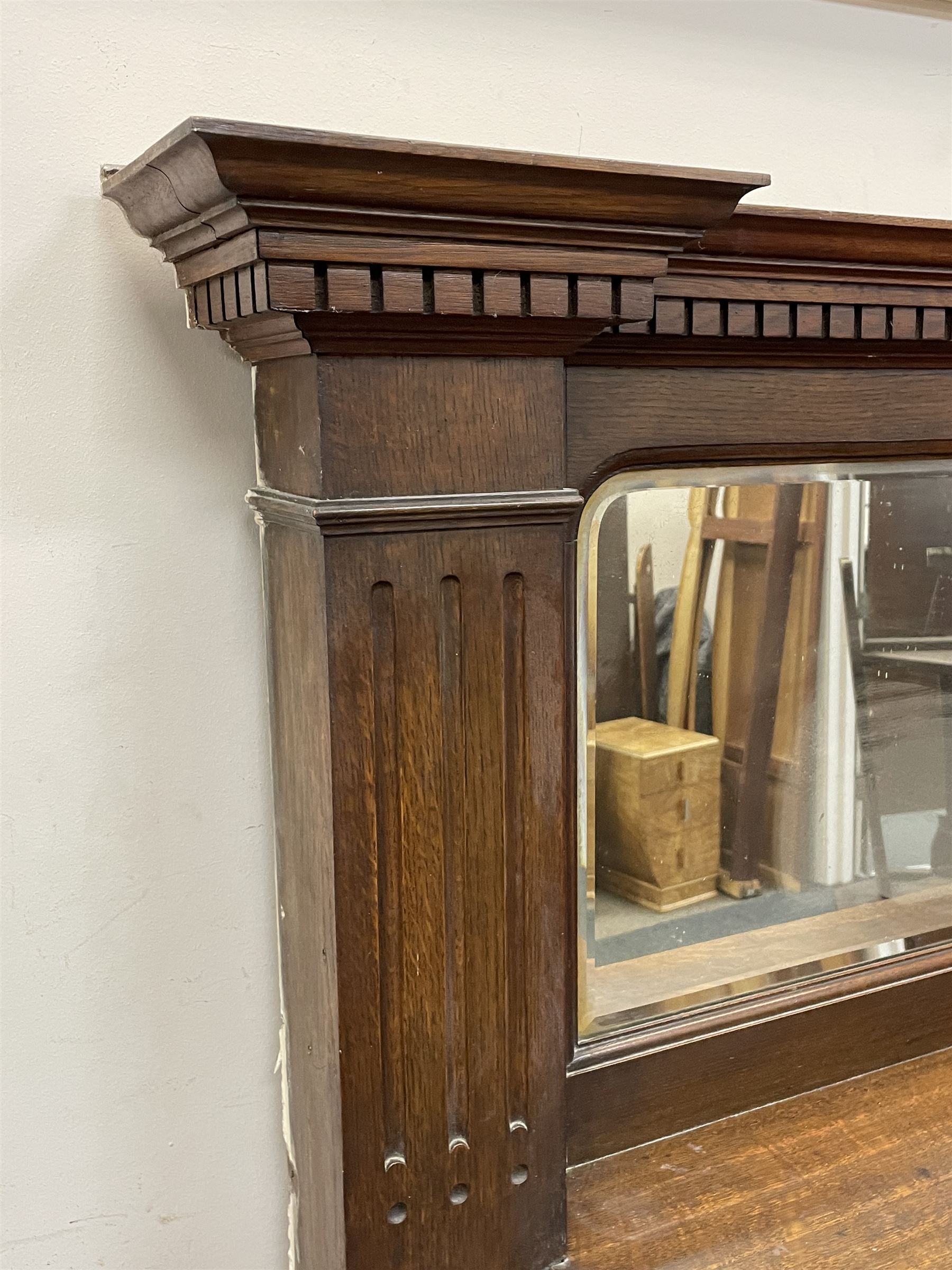 Late 19th/early 20th century fireplace, oak surround with projecting dentil cornice over bevelled mirror and shelf, with copper inset decorated with Heraldic knot motifs and rivets, together with various fire accessories 