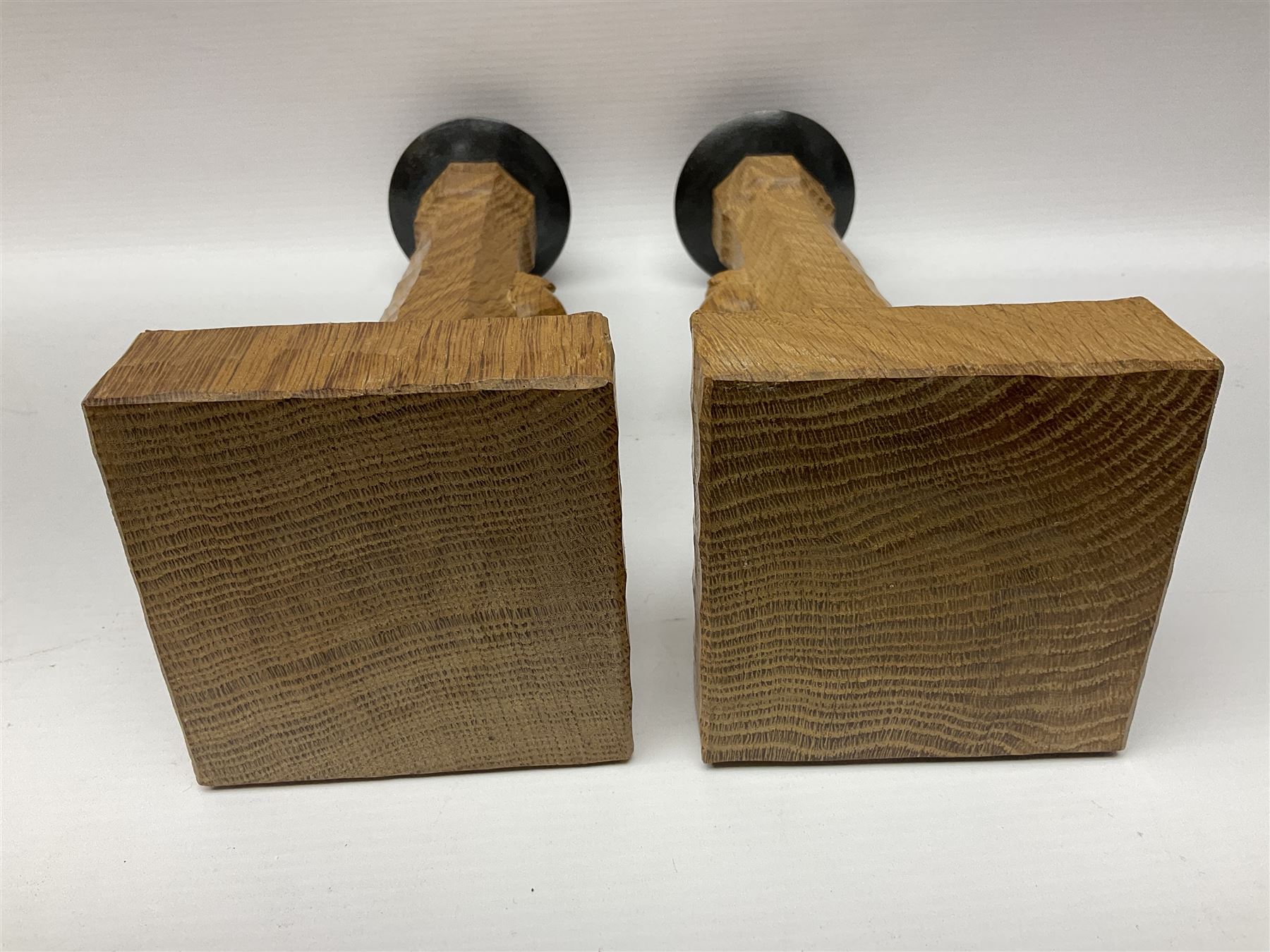 Mouseman - pair of tooled oak candlesticks, wrought iron sconce with drip tray over tapered octagonal column carved with mouse signature, terminating to stylised leaf carved square base, by the workshop of Robert Thompson, Kilburn
