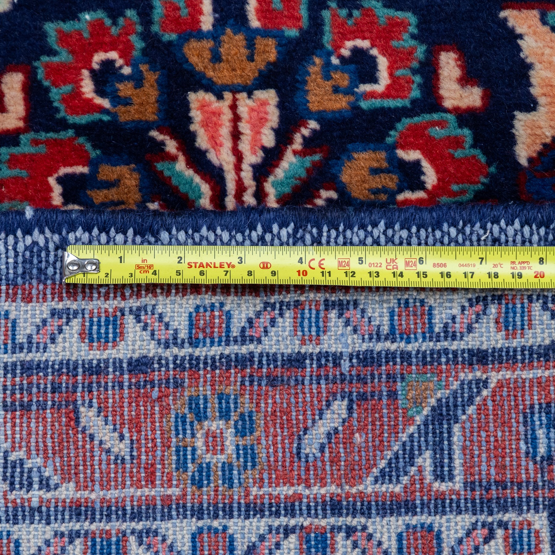 North West Persian runner, the indigo field decorated with repeating symmetrical floral sprays, rosettes and curling foliage in coral, ivory and pale blue tones, enclosed by a red ground trailing flowerhead border and narrow patterned guard bands 