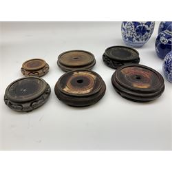 Six Chinese ginger jars, predominantly of blue and white design decorated with blossoming branches, all with lids, housed on various hardwood carved stands, some with character marks beneath