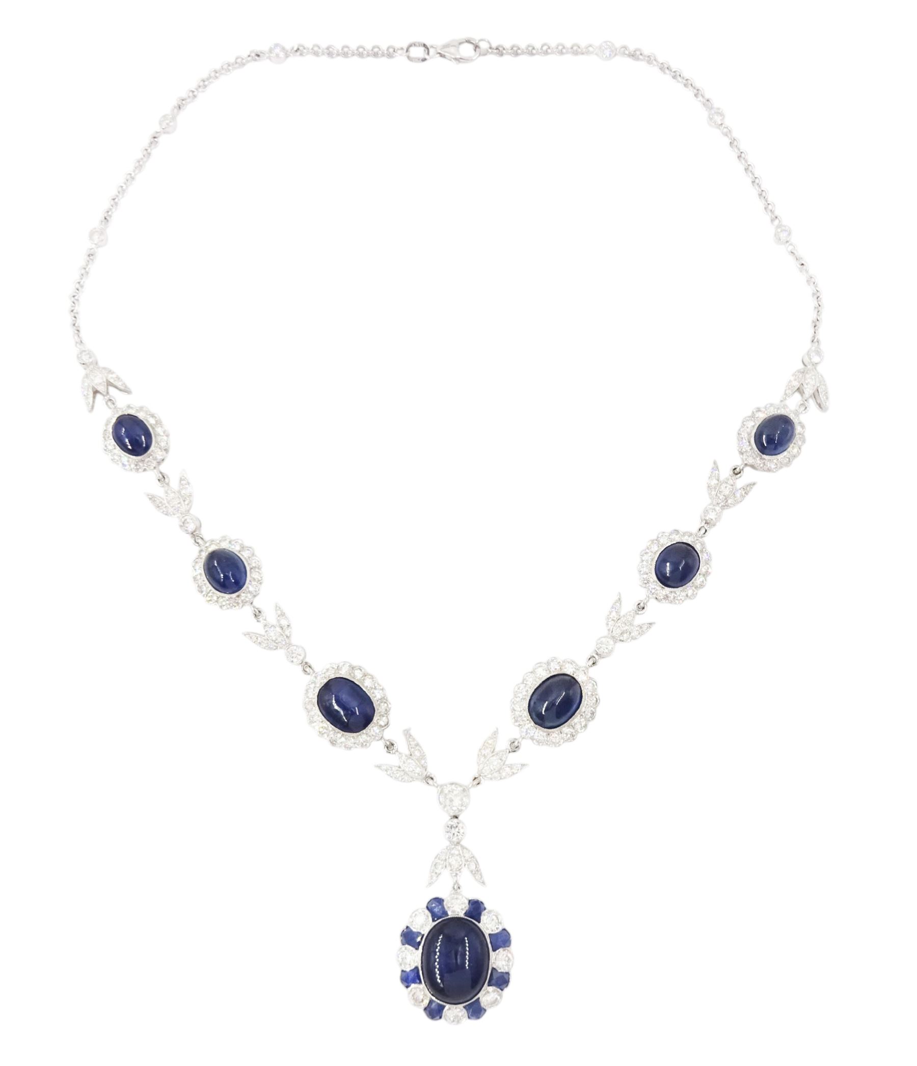 18ct white gold sapphire and diamond milgrain set necklace, oval cabochon cut sapphire surrounded by eight round brilliant cut diamonds and eight French cut sapphires, suspending from a diamond set leaf pendant, single round brilliant cut diamond and a larger old cut diamond, the chain set with six graduating cabochon cut sapphires, each surrounded by diamonds and spaced by a single diamond and a diamond set leaf, to a belcher link chain necklace, hallmarked, total sapphire weight approx 27.00 carat, total diamond weight approx 7.50 carat