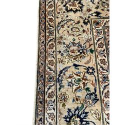Persian Kashan ivory ground carpet, floral design central medallion surrounded by trailing and interlaced leafy branches with palmettes and flower heads, matching patterned border with guard stripes 