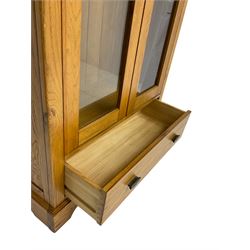 Tall oak display cabinet, projecting cavetto cornice over two glazed doors and single drawer, on bracket feet