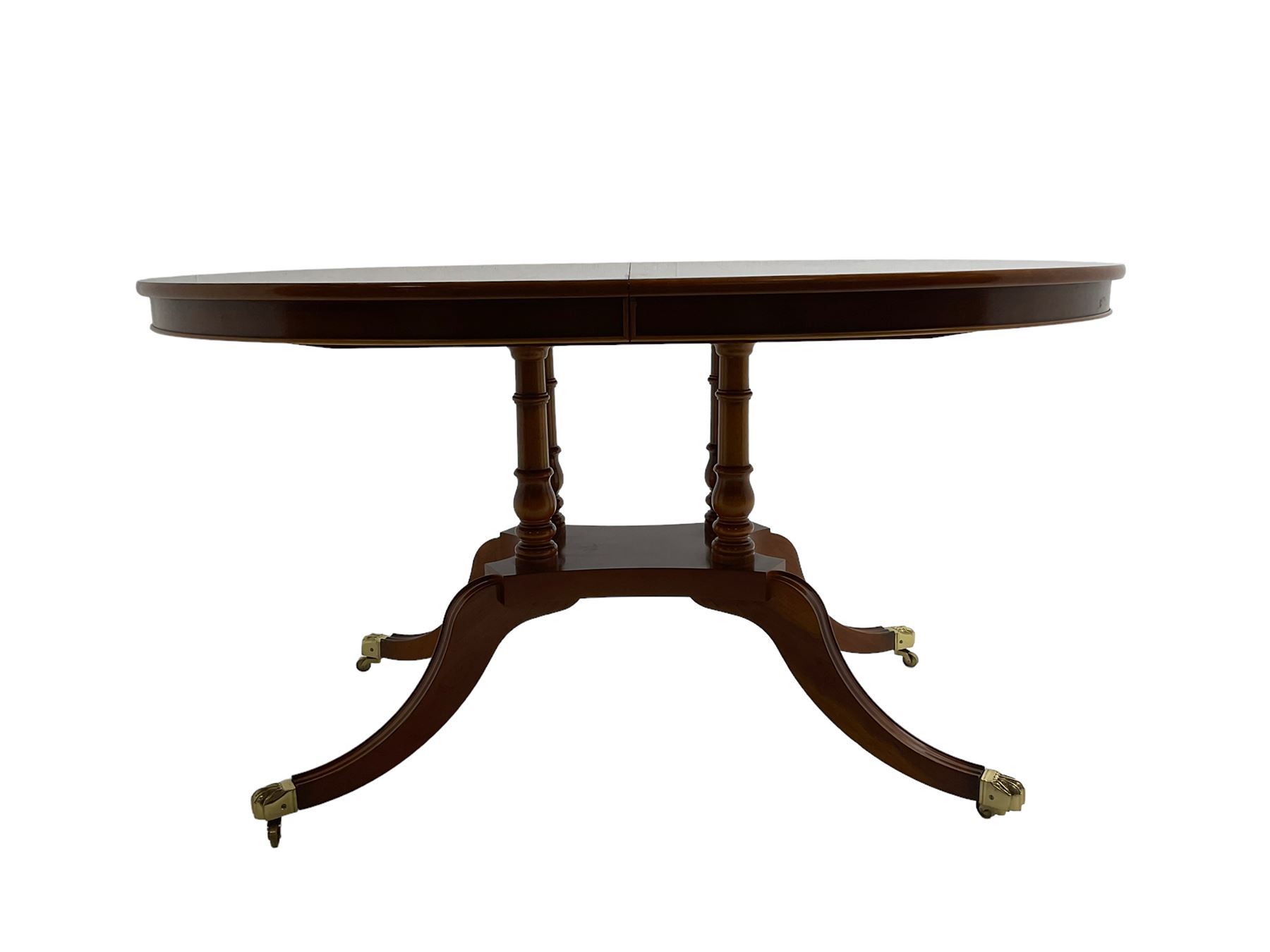 Georgian design yew wood twin pedestal dining table, circular top over four turned columns joined by base, raised on splayed and fluted cabriole supports with paw feet and castors (140cm x 108cm x 77cm); with set six (4+2) Georgian style yew wood dining chairs, middle rail pierced and carved with flowerhead and extending foliage, upholstered drop in seat, raised on turned tapering supports (50cm x 47cm x 86cm)