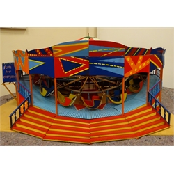  Large brightly painted electrically operated scratch built wooden and metal fairground roundabout with eighteen sleigh shaped cars revolving above an undulating boardwalk beneath a red and white cloth covered canopy with sets of steps to either side D103cm excluding steps H46cm  
