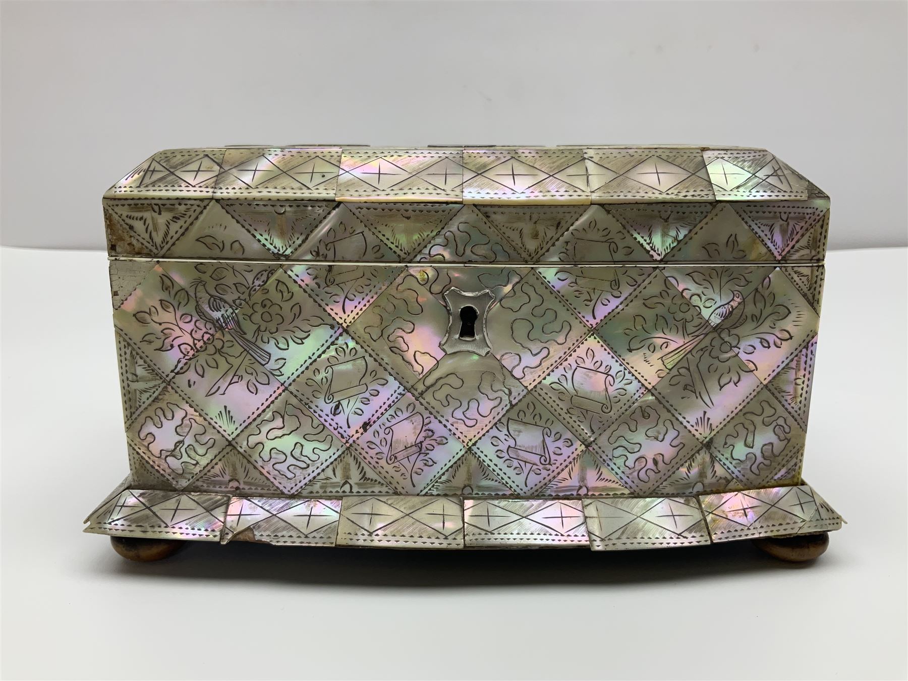 Victorian mother of pearl tea caddy, of rectangular bow-fronted form, the body with floral, bird and geometric engraved mother of pearl panels, white metal shield plaque to the cover inscribed with the initials G.J.A and similar escutcheon, the two division interior with ivory edging and two panelled mother of pearl lids, on four vegetable ivory bun feet L20cm, together with a similar style mother of pearl card case (2) This item has been registered for sale under Section 10 of the APHA Ivory Act