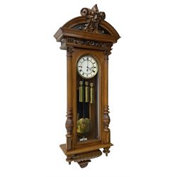 German- Late 19th century 8-day walnut cased Vienna regulator wall clock c1870,  with a broad arched pediment and heavily carved grotesque to the centre, carved frieze beneath with reeded columns to the front of the fully glazed door, carved ogee plinth and pendants to the base, two part enamel dial with Roman numerals and pierced steel hands, ebonised pendulum rod with a brass faced bob and beat plate, three matching brass cased weights and pulleys, grand sonnerie three train striking movement with a deadbeat escapement striking the quarters and hours on two coiled gongs. 
With repeat work.