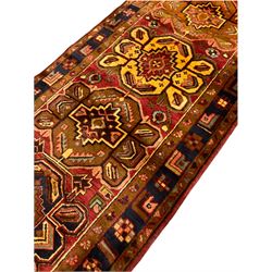 Persian Heriz golden red ground runner, the field decorated with five medallions and geometric motifs, repeating geometric design guarded boarder 