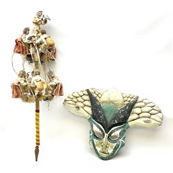 Mid 20th century Brinquinho folk art instrument from Madeira, Portugal, with wood dolls dressed in traditional costume with castanets and bottle caps, L94cm, together with a green, black and white festival mask