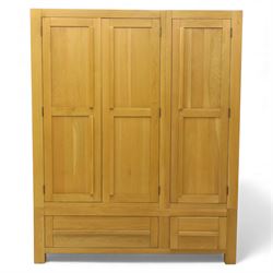 Modern light oak triple wardrobe,  three panel doors with integrated handles enclosing full-height hanging rails, the lower section fitted with two flush-front drawers, square uprights