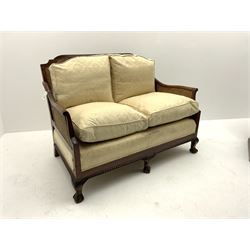Late 20th century mahogany framed bergere two seat sofa, double cane worked back and arms, upholstered in pale floral pattered fabric, carved apron above ball and claw supports 