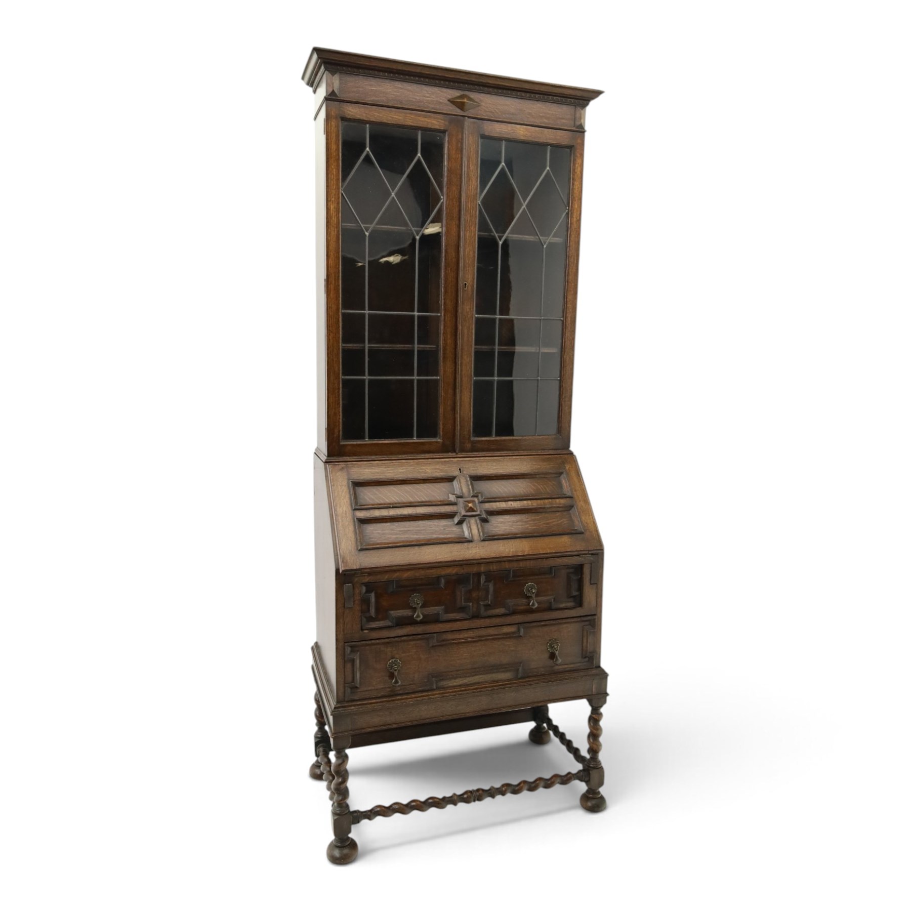 Early 20th century Jacobean Revival oak bureau-bookcase, astragal glazed doors enclosing two adjustable shelves, over geometric panelled fall-front enclosing fitted interior, over two drawers, raised on a spiral-turned base with barley-twist stretchers and compressed bun feet