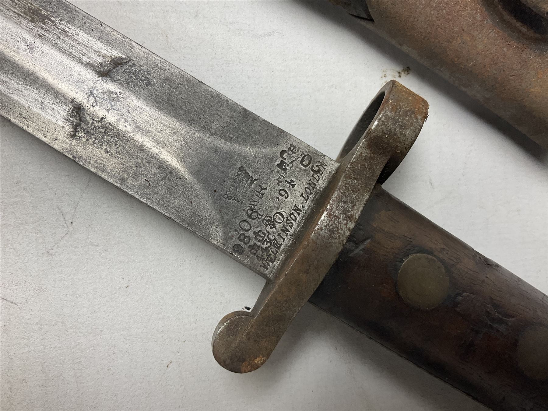 British No 7 MKI knife bayonet with 20cm single edged fullered clipped point blade;  blackened steel, large muzzle ring cross-guard; blackened swivelling pommel marked 'F5H'; red Tufnol composite grips; in blackened steel scabbard L33cm overall; British Pattern 1888 bayonet with scabbard; and German Ersatz bayonet with scabbard (3)