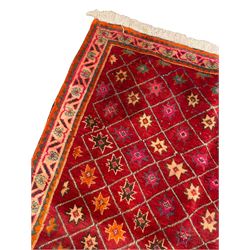 Persian Shiraz red ground rug, the field intersected with criss-cross lines and decorated with star motifs, the border decorated with flower head motifs