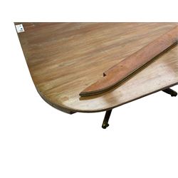 Regency mahogany dining table, rectangular top with rounded corners and reeded edge, raised on square pedestal with platform, terminating to sabre supports with brass cups and castors