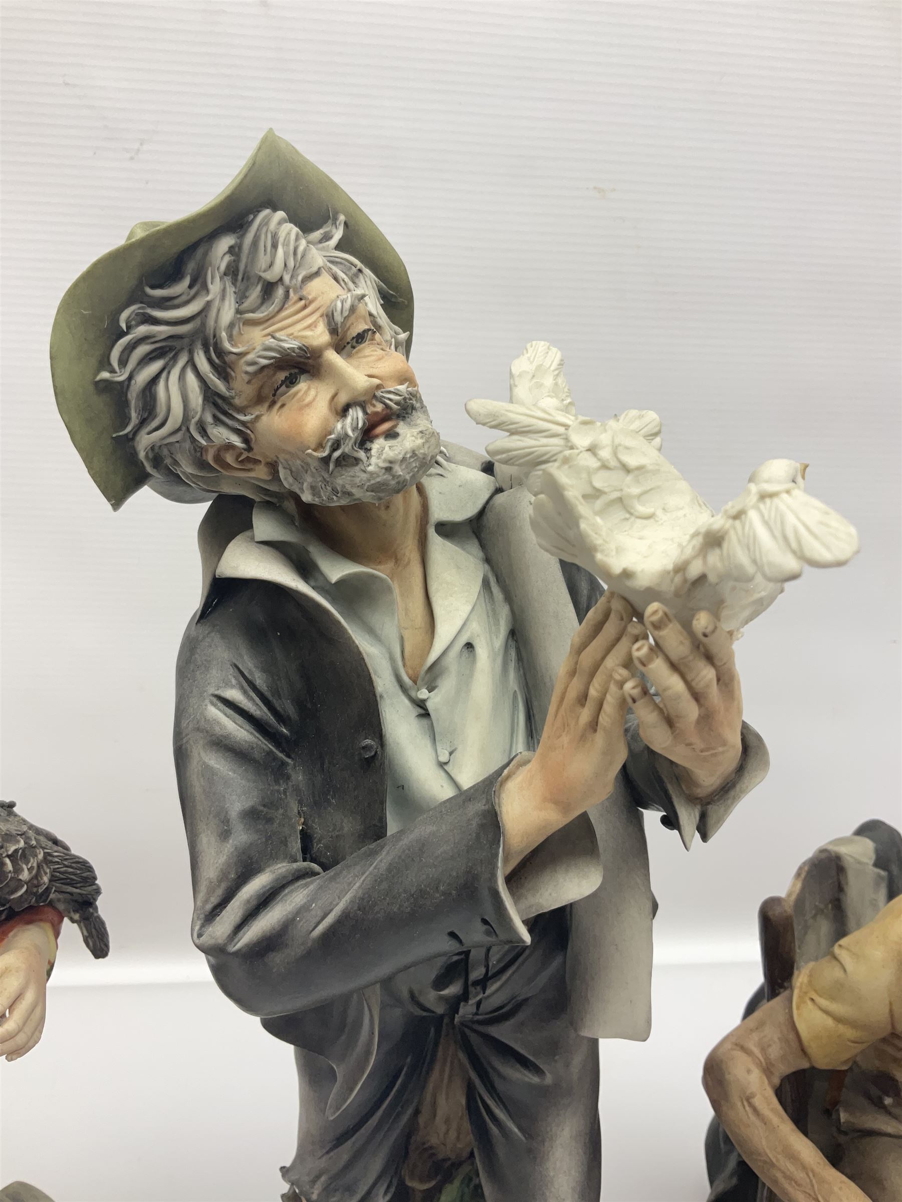 Three Capodimonte figures, to include The Kind Heart Man, modelled by Cortese as a tramp with two doves, The Young Falconer by Maria Angela and another modelled as a tramp darning his socks, all with printed marks, tallest H39cm