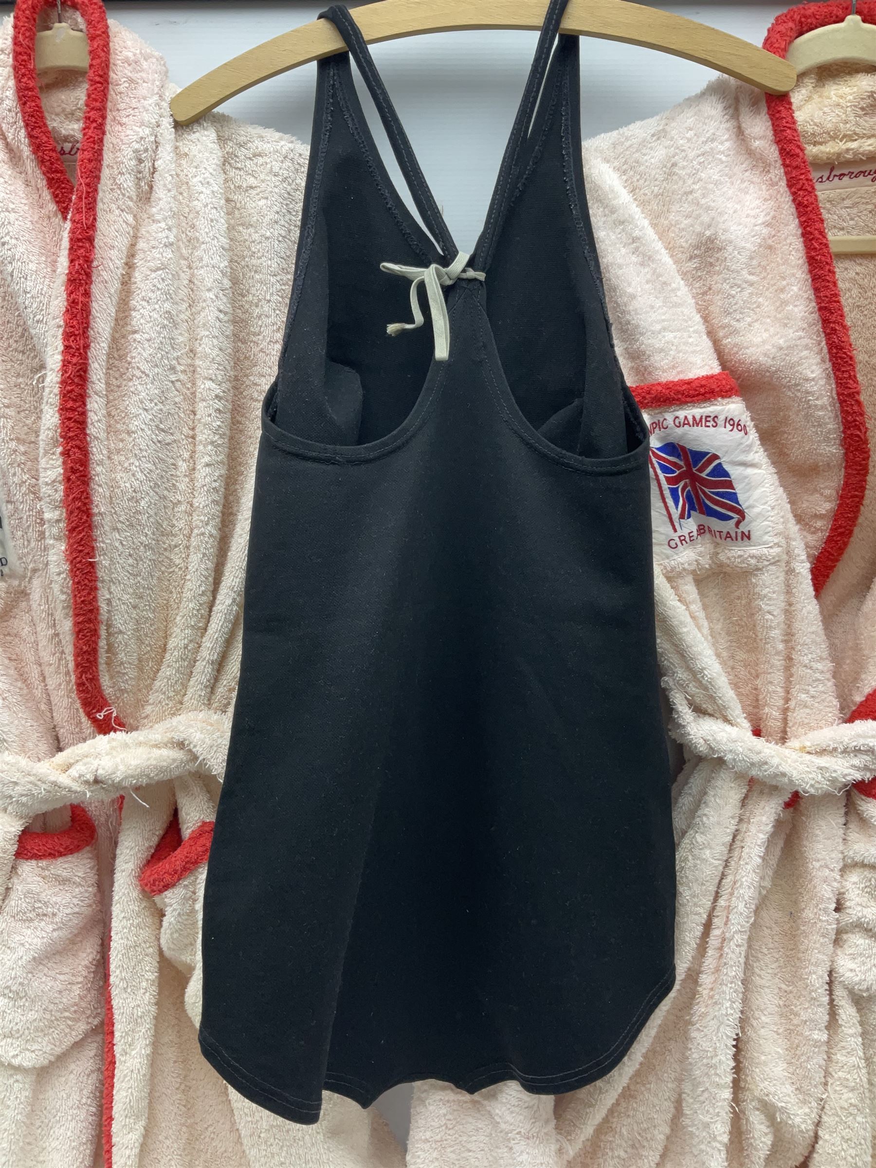 On the direct instructions of Anita Porter nee Lonsbrough Great British Olympic and Commonwealth Games gold medal winning swimmer - collection of early and international memorabilia comprising original Huddersfield Bath Club track suit top bearing eight stitched on cloth badges including British Empire & Commonwealth Games 1958 England Team, YSASA, North Eastern Counties ASA, ESSA Division 3,  English Schools Swimming Association winner etc
The swimming costume Anita wore at the 1958 Commonwealth Games in Cardiff, her first major championships, where she won two gold medals. The grey elastic on the sides, in those days, she would use to make it tighter and more streamlined.
Blue track suit from the 1960 Olympics which she wore on the podium receiving the gold medal.
1960 pool side towelling robe used at the Rome Olympics (interesting to note her name is spelt wrong on the embroidered label).
1962 Commonwealth Games pool side towelling robe used in Perth Australia when winning three Gold medals. 
It was also this year she became BBC Sports Personality of the year, the first female to do so.
Her 'lucky' pool side towel which she took with her to every event she competed in and which can be seen round her neck in many official celebratory photographs. Copies of some of these photographs are included for identification.
In addition there are two souvenir programmes of an evening event to honour Anita at The Theatre Royal Huddersfield and she has kindly signed the front cover on one of these.