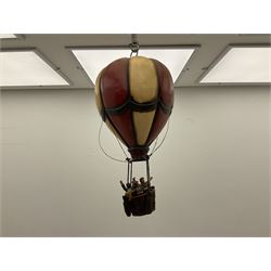 Painted wooden hanging model of a hot air balloon group, the balloon above a wicker basket complete with sandbags and figures, together with a similar example with a clown figure below, H68cm