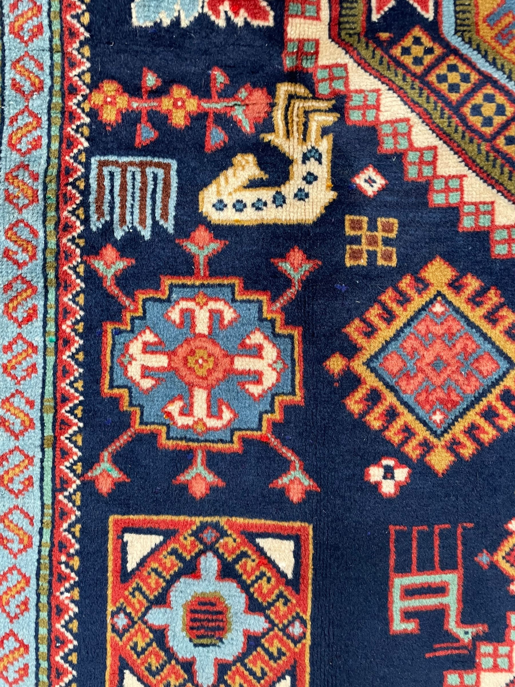 Persian Ardabil indigo ground rug, four interconnected lozenge medallions surrounded by ewer, bird, dragon, camel and geometric motifs, hooked border within guard stripes 