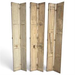 Set of three French 19th century painted pine folding window shutters of tall form, each comprising two hinged leaves with three graduated raised and fielded panels, in antique cream-painted finish