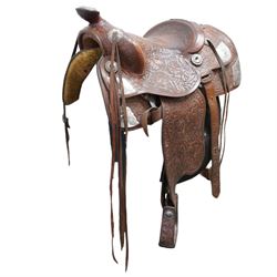 Keyston Bros (San Francisco) - 1930s/1940s 18’ American leather and silver mounted Western Parade saddle, the mahogany-tone leather body heavily hand-carved in a deep California Poppy floral pattern, surmounted by a ‘Bear Trap’ pommel fitted with an oval horn cap featuring a silver medallion of a cowboy on a bucking horse, further embellished with engraved sterling silver mountings, including large domed conchos, full-dress skirt corner plates, and a continuous cantle trim band, together with the associated girth, stirrups and leathers