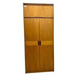 William Lawrence - mid-20th century teak double wardrobe, upper storage section over twin doors featuring recessed handles and contrasting horizontal panel, enclosing hanging rail compartment, towel rail, mirror, shelves and drawer, on plinth base with concealed castors